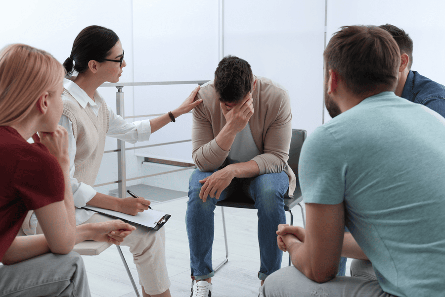 Support group session at Axiom Care, where a distressed man experiencing methamphetamine withdrawal symptoms receives guidance and encouragement.