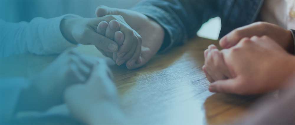 people holding hands at a table