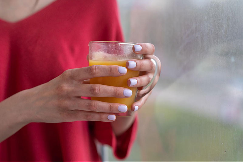 Woman Wearing Red Shirt Holding Glass of OJ