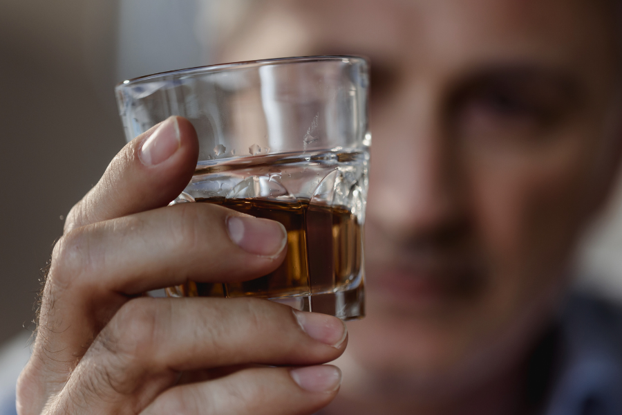 a man looks at a glass of liquor