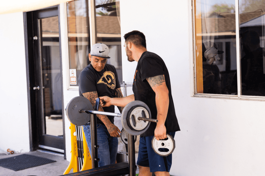 Two men lifting weights outdoors at Axiom Care, using fitness as a tool for staying grounded in early recovery