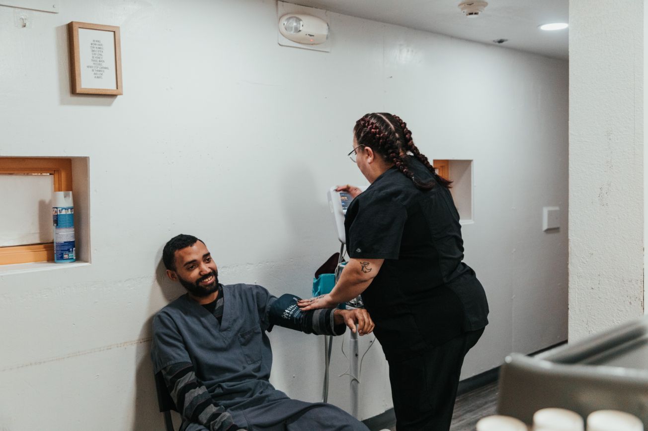 Female nurse taking blood pressure from a man at an AXIOM Recovery Center